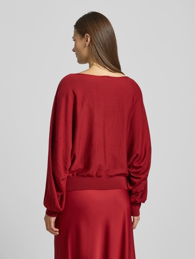 Vrouwenmodel draagt oversized scharlakenrode wollen trui met boothals, geribde boorden, rugaanzicht, Oversized Strickpullover mit U-Boot-Ausschnitt Modell 'GERLINA' van Drykorn, puur scheerwol.