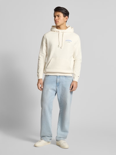 Mannenmodel draagt Regular Fit Hoodie aus reiner Baumwolle van Tommy Jeans in effen crème, label-stitching, kangoeroezak, sweatstof, katoen, volledig lichaam van voren