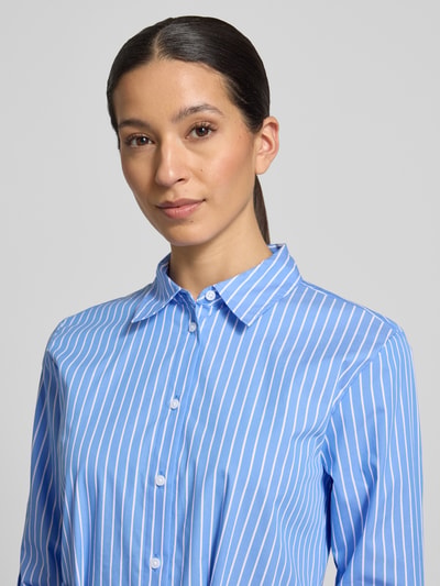 Vrouwenmodel draagt 'Hemdblusenkleid met afneembaar stoffen band' van comma in blauw-witte strepen, katoenmix, getailleerde pasvorm, overhemdkraag, met lange mouwen, knoopsluiting, context: dames overhemdjurk, midilengte, ruglengte maat 36: 120 cm, borstwijdte maat 36: 45 cm, mouwlengte maat 36: 59 cm. Nahaufnahme bovenlichaam.
