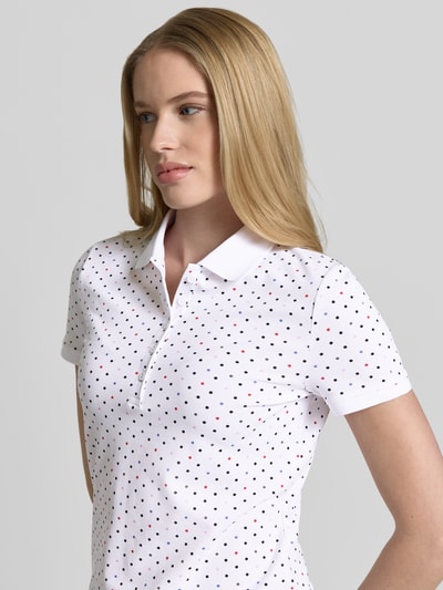 Kobiece model prezentuje Slim Fit Poloshirt mit Baumwoll-Anteil von Christian Berg Woman, biały z drobnymi kolorowymi kropkami, krój slim fit, bawełna z elastanem, kołnierzyk polo, krótki rękaw, długość tyłu w rozmiarze S: 61 cm, zbliżenie na górną część ciała