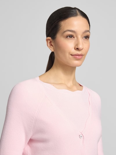 Frauenmodel trägt Strickcardigan aus Viskose-Mix von Christian Berg Woman in zartem Rosa, tailliert mit Rüschen, Nahaufnahme Oberkörper.