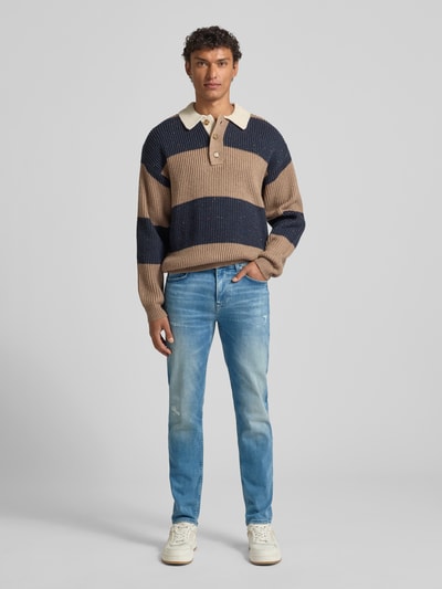 Männermodel trägt Slim Fit Jeans aus Baumwoll-Mix Modell 'DELAWARE' von BOSS Orange, blaue Denim-Optik, Ganzkörperansicht von vorne.