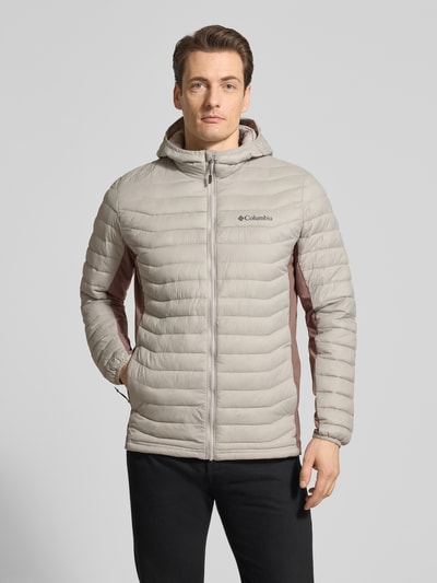 Mannenmodel draagt Steppjacke mit Kapuze und Logo van Columbia in regular fit, lichtbeige met bruin, ritssluiting, logoprint, Ganzkörperansicht von vorne. Ruglengte maat M 72 cm, schouderbreedte 47 cm, borstwijdte 52 cm, mouwlengte 69 cm.