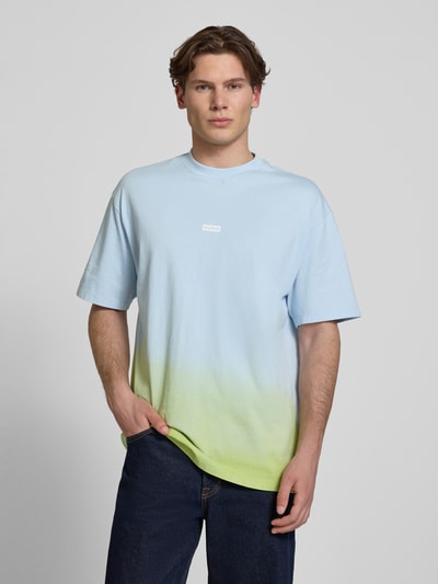 Männermodel trägt Loose Fit T-Shirt aus reiner Baumwolle Modell 'NALONO_F' von Hugo Blue in Farbverlauf Hellblau zu Gelb, Logo Details, Rundhals, Kurzarm, Ganzkörperansicht von vorne.