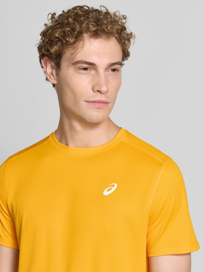 Męski model nosi t-shirt z nadrukiem z logo Model 'CORE' od ASICS TIGER, prosty krój, okrągły dekolt, Długość tyłu w rozmiarze M: 72 cm, zbliżenie na górną część ciała