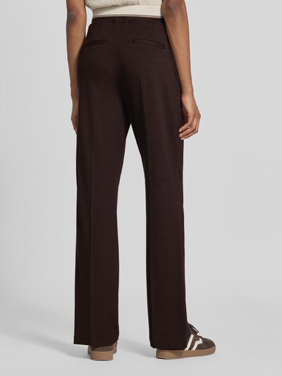Frauenmodel trägt Straight Fit Hose aus Viskose-Mix von Milano Italy in Dunkelbraun, elastischer Bund, Ziernaht, Ganzkörperansicht Rückansicht.