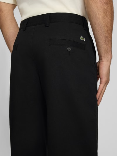 Männermodel trägt schwarze Loose Fit Weite Hose aus Baumwoll-Mix von Lacoste, Herren Weite Hose, Nahaufnahme Rückansicht.