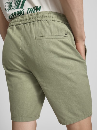 Männermodel trägt Regular Fit Shorts aus Baumwoll-Leinen-Mix Modell 'LINUS' von Only & Sons in Olivgrün, elastischer Bund, Rückansicht, Nahaufnahme Oberkörper bis Knie.