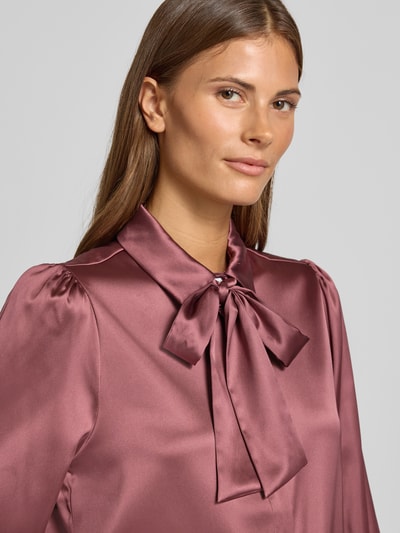 Vrouwenmodel draagt Regular Fit Hemdbluse aus Satin van Christian Berg Woman Selection in bordeaux satijn met sierstrik, close-up bovenlichaam