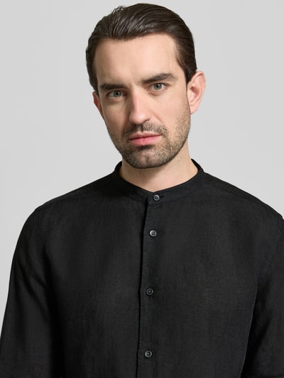 Männermodel trägt Slim Fit Leinenhemd aus reinen Leinen mit Stehkragen von OLYMP Level Five in Schwarz, Nahaufnahme Oberkörper. Langärmeliges Design mit durchgehender Knopfleiste, reine Leinenstruktur sichtbar, sportliche Manschetten.