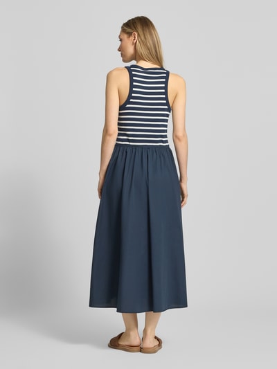 Modelka kobieca nosi A-Linie Freizeitkleid aus reiner Baumwolle od Tommy Hilfiger, granatowe z białymi poziomymi paskami, bawełniany materiał, szerokie ramiączka, długość maxi, boczne kieszenie, uniwersalny wzór, widok całej sylwetki z tyłu.