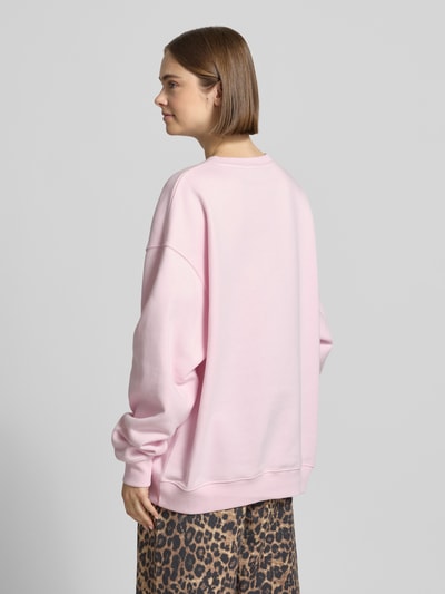 Frauenmodel trägt Oversized Sweatshirt mit Logo-Print von OH APRIL in Rosa, Baumwoll-Mix, Oversized-Fit, gerippter Rundhalsausschnitt, überschnittene Schultern, Ganzkörperansicht Rückansicht.