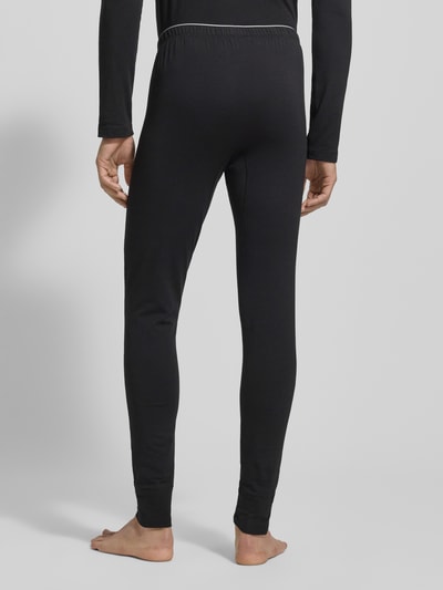 Männermodel trägt Stoffhose mit elastischem Bund von Schiesser, Baumwoll-Elasthan-Mix, körpernaher Schnitt, Ganzkörperansicht Rückansicht.