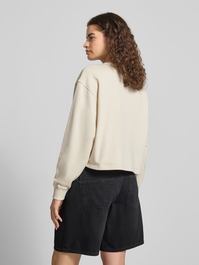 Kobiece model prezentuje bluzę Regular Fit Sweatshirt aus reiner Baumwolle Modell 'DAMASWEE_B_1' od Hugo Blue, kremowy kolor, czarna jeansowa szorty, widok całej sylwetki tyłem, damska bluza.