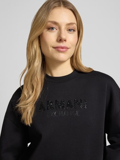 Kobiece modelka ma na sobie Sweatshirt mit Logo-Print und Rundhalsausschnitt od ARMANI EXCHANGE, mieszanka bawełny z dodatkiem streczu, krój loose fit, okrągły dekolt, nadruk z logo, czarny, miękka faktura, prosty krój, zbliżenie na górną część ciała