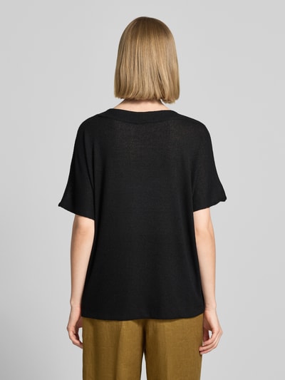 Frauenmodel trägt Strickshirt mit V-Ausschnitt Modell 'Delia' von Soyaconcept in Schwarz, lockere Passform, feine Textur, Rückenansicht, Ganzkörperansicht Rückansicht. Viskose-Mix mit Stretch-Anteil, Rückenlänge 60 cm bei Größe S.