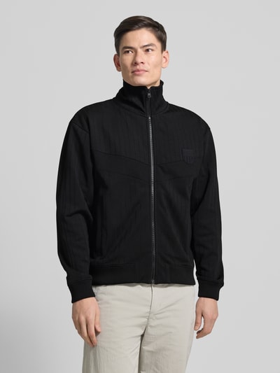 Männermodel trägt Regular Fit Sweatjacke aus Baumwoll-Mix Modell 'DAVRONTO' von HUGO in Schwarz mit Stehkragen, Ganzkörperansicht von vorne.