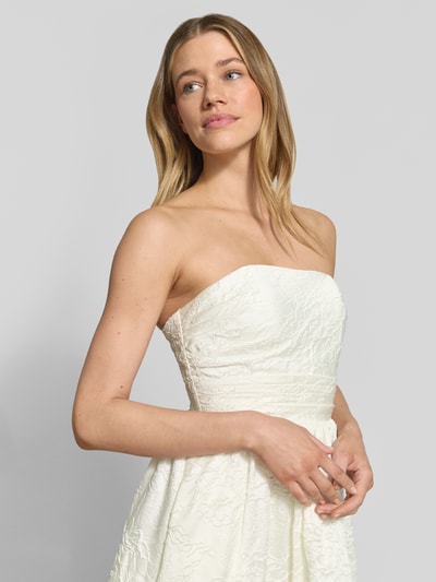 Frauenmodel trägt Minikleid mit floralem Allover-Stitching von Hey Kyla, tailliert, schulterfrei, weiße Struktur, Nahaufnahme Oberkörper.