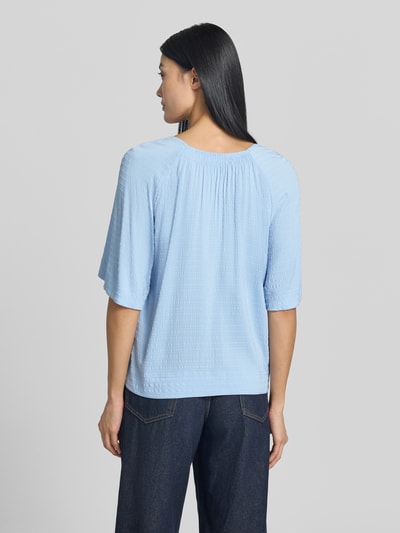 Frauenmodel trägt Relaxed Fit Kurzarmbluse aus Viskose-Mix von s.Oliver RED LABEL in Hellblau, strukturierte Oberfläche, Ganzkörperansicht Rückansicht.