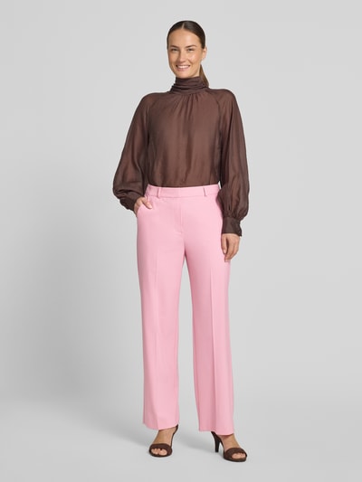 Frauenmodel trägt Stoffhose aus Viskose-Mix mit Gesäßleistentasche von Comma, rosa Farbe, Straight Fit, Bügelfalten, Ganzkörperansicht von vorne.