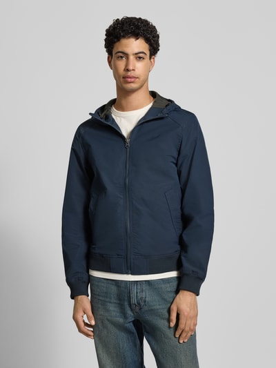 Männermodel trägt Regular fit Jack met logoprint model 'Track' van G-Star Raw, donkerblauw, steekzakken, opstaande kraag, met capuchon, elastische boorden, voorkant volledig zichtbaar, Ganzkörperansicht von vorne. Ruglengte maat M 65 cm, schouderbreedte 41 cm, borstwijdte 48 cm, mouwlengte 67 cm.
