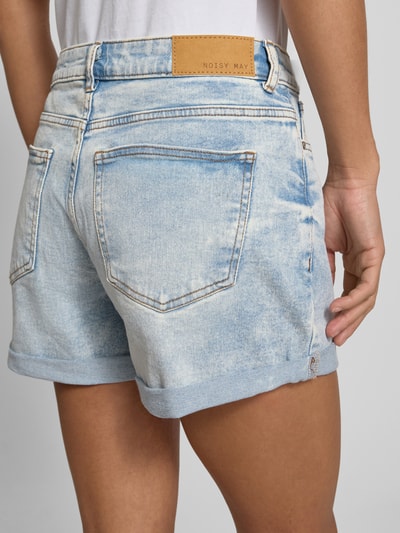 Frauenmodel trägt High Waist Jeansshorts mit Umschlag Modell 'MONI' von Noisy May aus hellblauem Baumwoll-Elasthan-Mix mit Eingrifftaschen, Regular-Fit, Bundweite 40 cm, Innenbeinlänge 9 cm, Detailaufnahme Rückansicht.