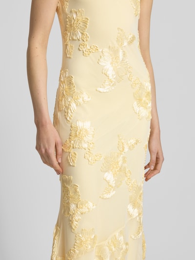 Kobieta modelka nosi eng anliegendes Abendkleid mit florale Details Modell 'QUINN' od Vero Moda, jednolity, krój slim fit, maxi, dekolt kwadratowy, cienkie ramiączka, prosty dół, żółty kolor, kwiatowe wypukłe tekstury, zbliżenie na tułów
