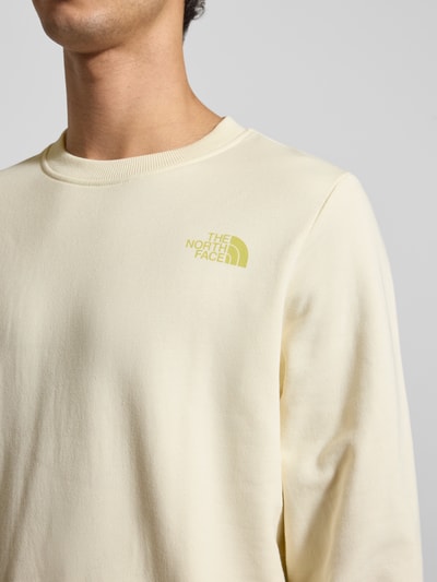 Männermodel trägt Sweatshirt mit Label-Print von The North Face in Creme, Reine Baumwolle, Regular-Fit, Rundhalsausschnitt, Nahaufnahme Oberkörper.