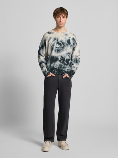Männermodel trägt Relaxed Fit Pullover aus reiner Baumwolle Modell 'SESTROY' von Hugo Blue mit Batik Allover-Muster, Ganzkörperansicht von vorne.