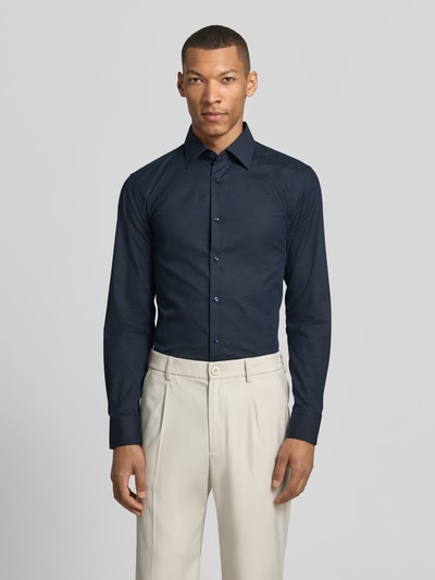 Męski model nosi Slim Fit Businesshemd aus Baumwoll-Mix Modell 'HANK' od BOSS, granatowe, gładkie, długi rękaw, popelina, widok na cały przód.