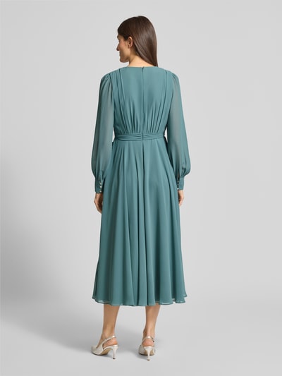 Vrouwenmodel draagt Regular Fit Midikleid mit Taillenband van Christian Berg Cocktail in teal, lang, semi-transparant, rugaanzicht.