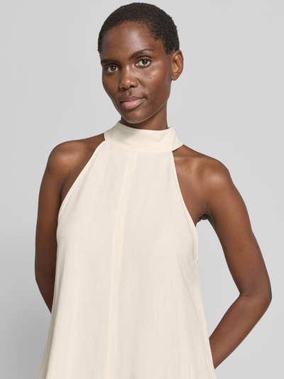 Frauenmodel trägt Minikleid mit Eingrifftaschen Modell 'Qileen' von Someday, cremefarbener Viskose-Mix mit Leinen-Anteil, Loose-Fit, Neckholder mit Knopfverschluss, Rückseitiger Cut-Out, Nahaufnahme Oberkörper.