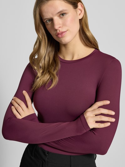 Frauenmodel trägt Slim Fit Langarmshirt mit Rundhalsausschnitt Modell 'LULA' von Pieces in unifarbener, dehnbarer Webstruktur, Nahaufnahme Oberkörper.
