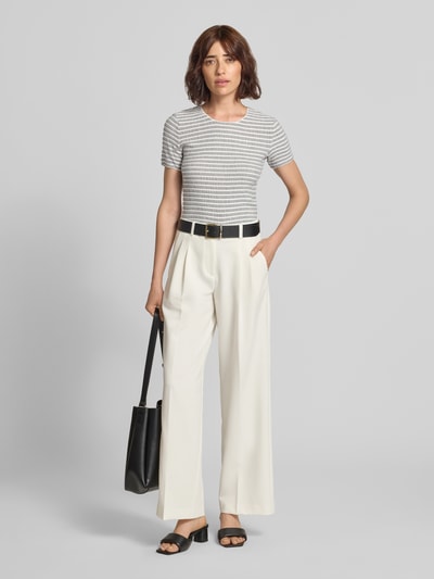 Frauenmodel trägt T-Shirt aus Viskose-Mix mit Rundhalsausschnitt von Emporio Armani, Strukturmuster, Allover-Look, Slim Fit, weiß-grau gestreift, kombiniert mit heller Hose, Produktlänge 50 cm bei Größe S, Ganzkörperansicht von vorne.