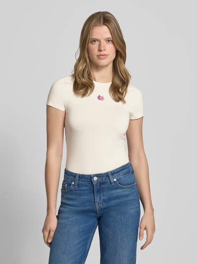 Frauenmodel trägt Slim Fit T-Shirt mit Motiv-Stitching von REVIEW, cremefarben, schmal geschnitten, elastischer Baumwoll-Mix, Nahaufnahme Oberkörper.