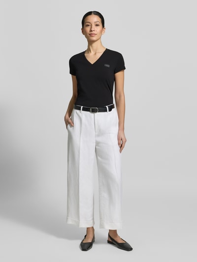 Frauenmodel trägt T-Shirt mit V-Ausschnitt und Label-Stitching von Armani Exchange aus Baumwoll-Elasthan-Mix, Regular-Fit, Ganzkörperansicht von vorne.