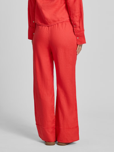 Vrouwenmodel draagt Leinenhose mit elastischem Bund und Tunnelzug van Christian Berg Woman in zuiver linnen, wijd been, rode kleur, ganzkörperansicht achteraan.