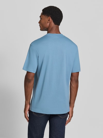 Männermodel trägt Regular Fit T-Shirt aus reiner Baumwolle von Lacoste in Hellblau, kombiniert mit dunkler Jeans, Ganzkörperansicht Rückansicht. Herren T-Shirt von Lacoste.