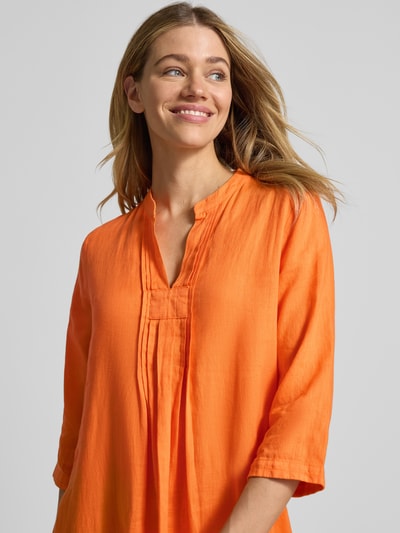 Frauenmodel trägt Tunikakleid aus Leinen mit 3/4-Arm von Emily Van den Bergh in kräftigem Orange, lockerer Schnitt, Nahaufnahme Oberkörper.