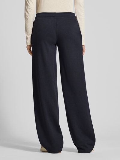 Frauenmodel trägt Wide Fit Sweatpants mit Viskose-Anteil von Review, dunkelblauer Baumwoll-Mix, elastischer Bund, Tunnelzug, Ganzkörperansicht Rückansicht