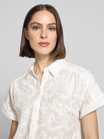 Frauenmodel trägt Regular Fit Bluse aus reiner Baumwolle Modell 'VIV' von Brax mit florales Allover-Muster in Weiß, Popeline, Hemdkragen, kurzarm, Label-Applikation, Rückenpasse, V-Ausschnitt, einreihige Knopfleiste; Struktur durch feine Stickerei-Textur, Nahaufnahme Oberkörper.