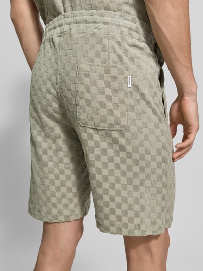 Männermodel trägt Regular Fit Shorts mit Label-Patch von Lindbergh, Baumwoll-Mix, Gesäßtasche, grün kariert, Ganzkörperansicht Rückansicht.