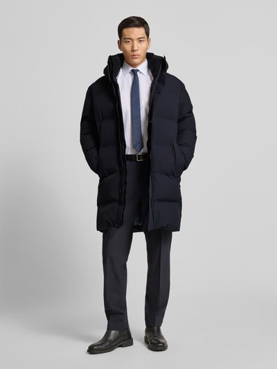 Männermodel trägt Steppmantel mit Kapuze von CINQUE in Dunkelblau, sichtbare Struktur, verdeckter Reißverschluss, Ganzkörperansicht von vorne. Regular Fit, Eingrifftaschen, Label-Detail, Maße laut Größe M.