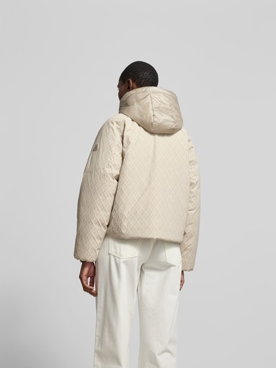Männermodel trägt Regular Fit Jacke mit Allover-Logo-Print von Moose Knuckles in Beige, Elastischer-Material-Mix, Kapuze, Zweiwege-Reißverschluss, Rückenlänge 60 cm, Brustweite 59 cm, Ärmellänge 63 cm, Ganzkörperansicht Rückansicht.
