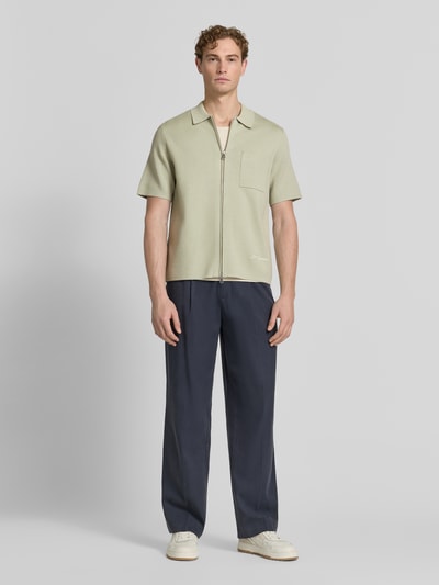 Męski model nosi Slim Fit Poloshirt mit Zweiwege-Reißverschluss Modell 'RICO' von Samsøe Samsøe, mieszanka wiskozy z dodatkiem streczu, krój slim fit, brustasza, długość tyłu w rozmiarze M 67 cm, jasna zieleń, gładka struktura, Ganzkörperansicht von vorne.