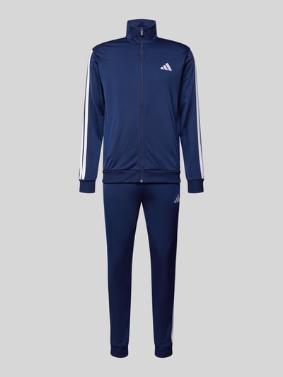 Produktfoto, 'Trainingsanzug mit elastischen Abschlüssen' von adidas Sportswear, granatowy kolor, prosty krój, logo, detale, elastyczne wykończenia, kurtka treningowa z zamkiem błyskawicznym, spodnie dresowe z elastycznym pasem, wpuszczane kieszenie, szerokość w rozmiarze M: 36 cm, długość tyłu w rozmiarze M: 71 cm, szerokość ramion w rozmiarze M: 46 cm, długość rękawów w rozmiarze M: 63 cm, długość wewnętrzna nogawki w rozmiarze M: 75 cm