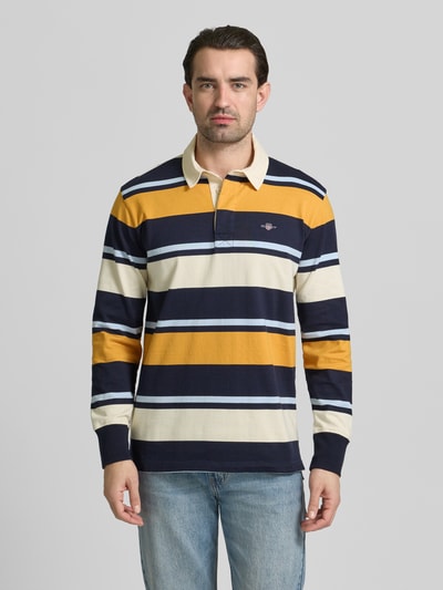 Männermodel trägt Sweatshirt mit Polokragen und Label-Stitching von Gant, gestreift in Gelb, Blau, Creme, Baumwolle, Regular Fit, Ganzkörperansicht von vorne.