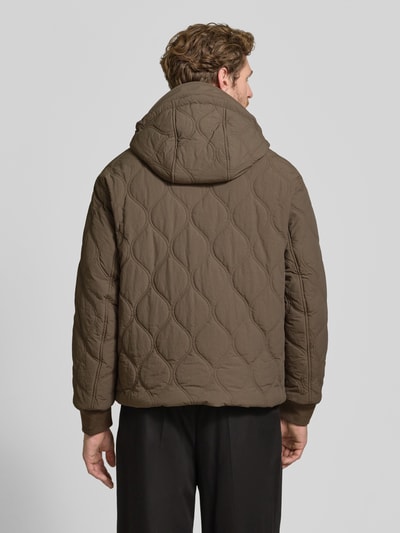 Männermodel trägt Jacke mit Steppnähten und Label-Detail von Armani Exchange in Braun, Struktur durch Steppnähte, Ganzkörperansicht Rückansicht. Rückenlänge 69 cm, Schulterbreite 46 cm, Brustweite 59 cm, Ärmellänge 67 cm, Regular Fit, Kapuze mit Tunnelzug, Zweiwege-Reißverschluss, Eingrifftaschen mit Knopfverschluss.
