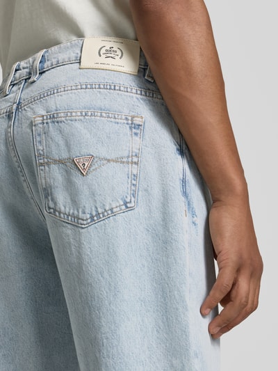 Männermodel trägt Straight Fit Jeans im 5-Pocket-Design Modell 'Damon' von Guess in Hellblau, reine Baumwolle, Nahaufnahme Rückansicht.