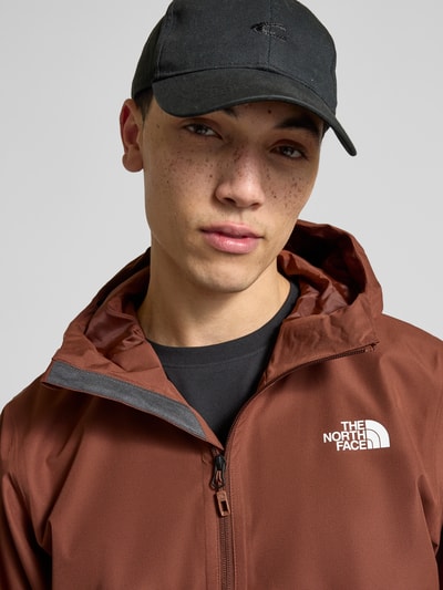 Männermodel trägt Jacke mit Kapuze von The North Face in Braun mit Label-Print und Reißverschlusstaschen, Nahaufnahme Oberkörper.